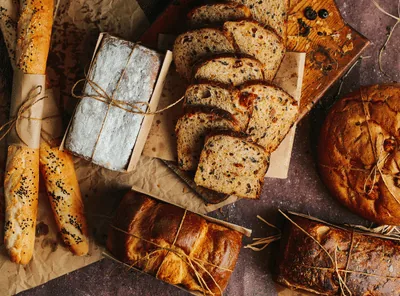 Loaves, rolls and studded breads laid out on a table, fresh from a home oven.